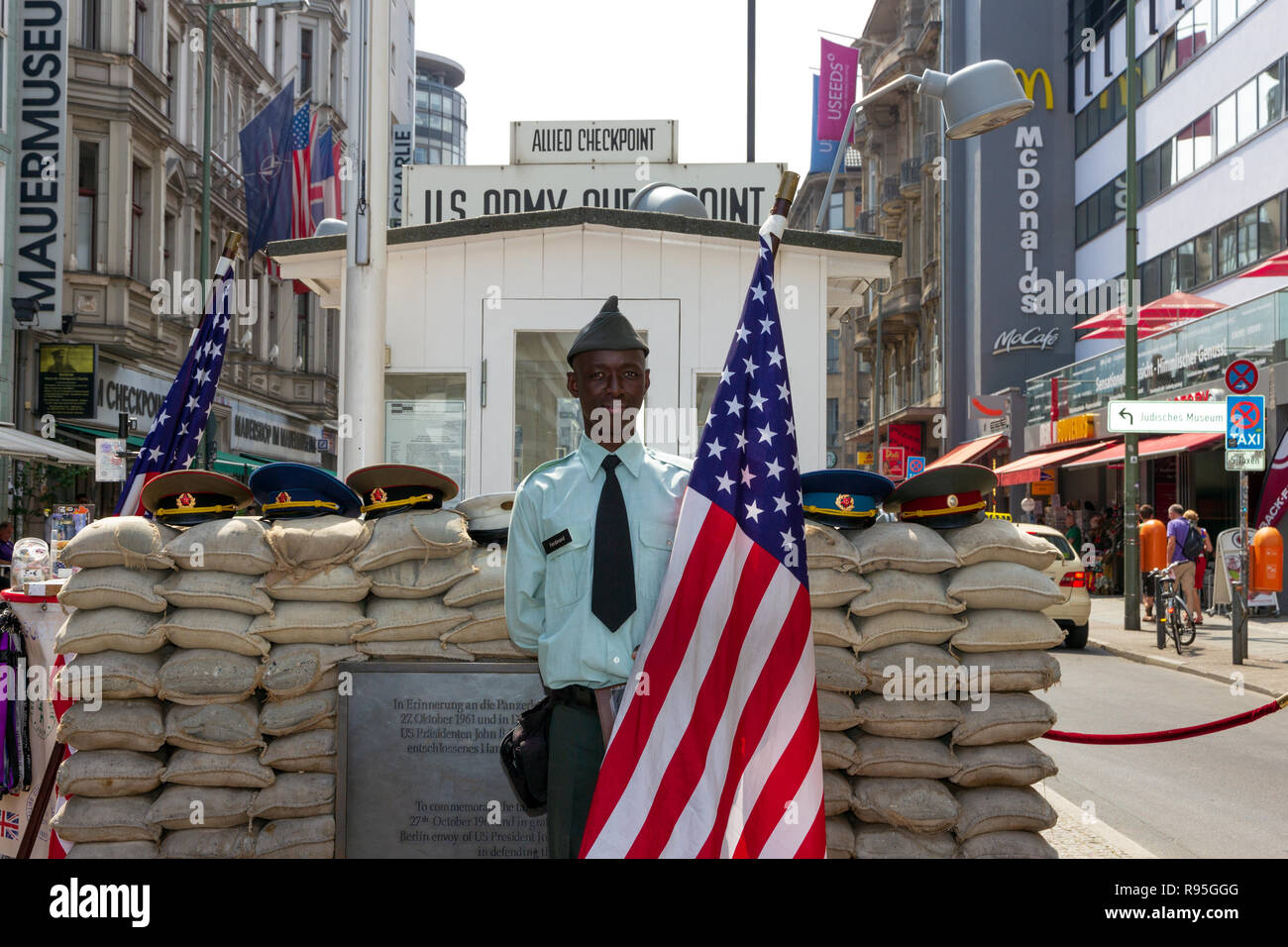 BERLIN, DEUTSCHLAND - 23. MAI 2014: der Mann, der als Soldat der US-Armee posing steht mit der amerikanischen Flagge am ehemaligen Allied Checkpoint Charlie. Heutzutage diese Seite Stockfoto