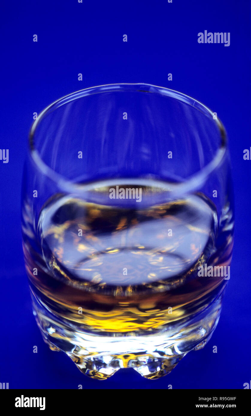 Alkoholisches Getränk im Glas auf blauem Hintergrund Stockfoto