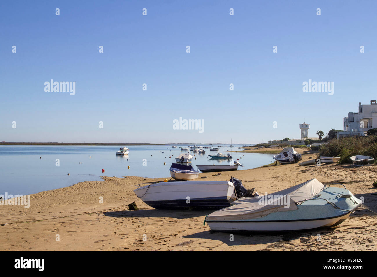 Faro, Portugal. .BLICK auf den Strand auf der Ria Formosa Lagune Seite der Faro Insel mit kleinen Booten gebunden und in der Lagune selbst vertäut. Stockfoto