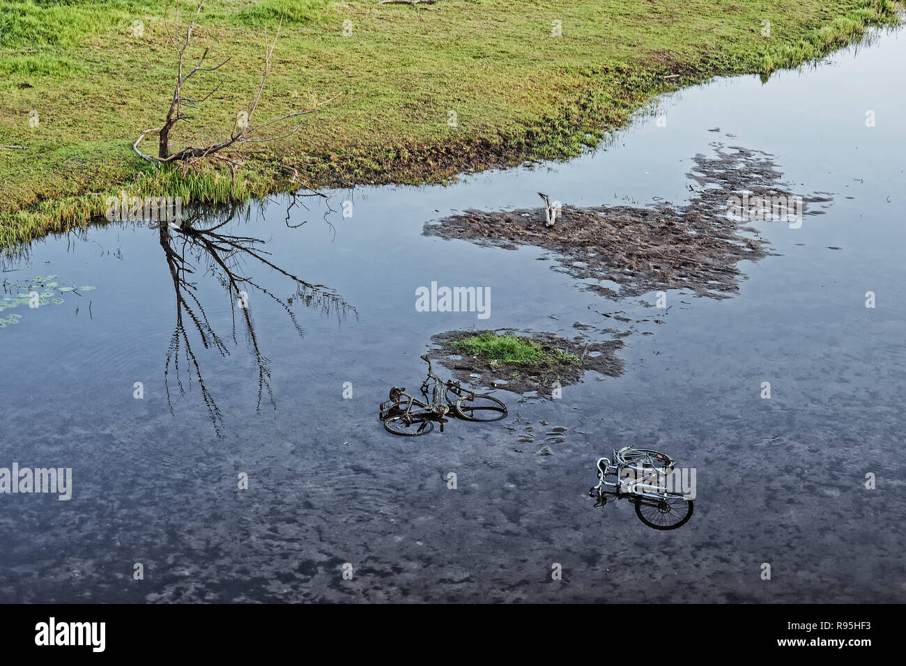 Entsorgen Sie zwei Fahrräder in einem Fluss als Symbol der Umweltverschmutzung Stockfoto