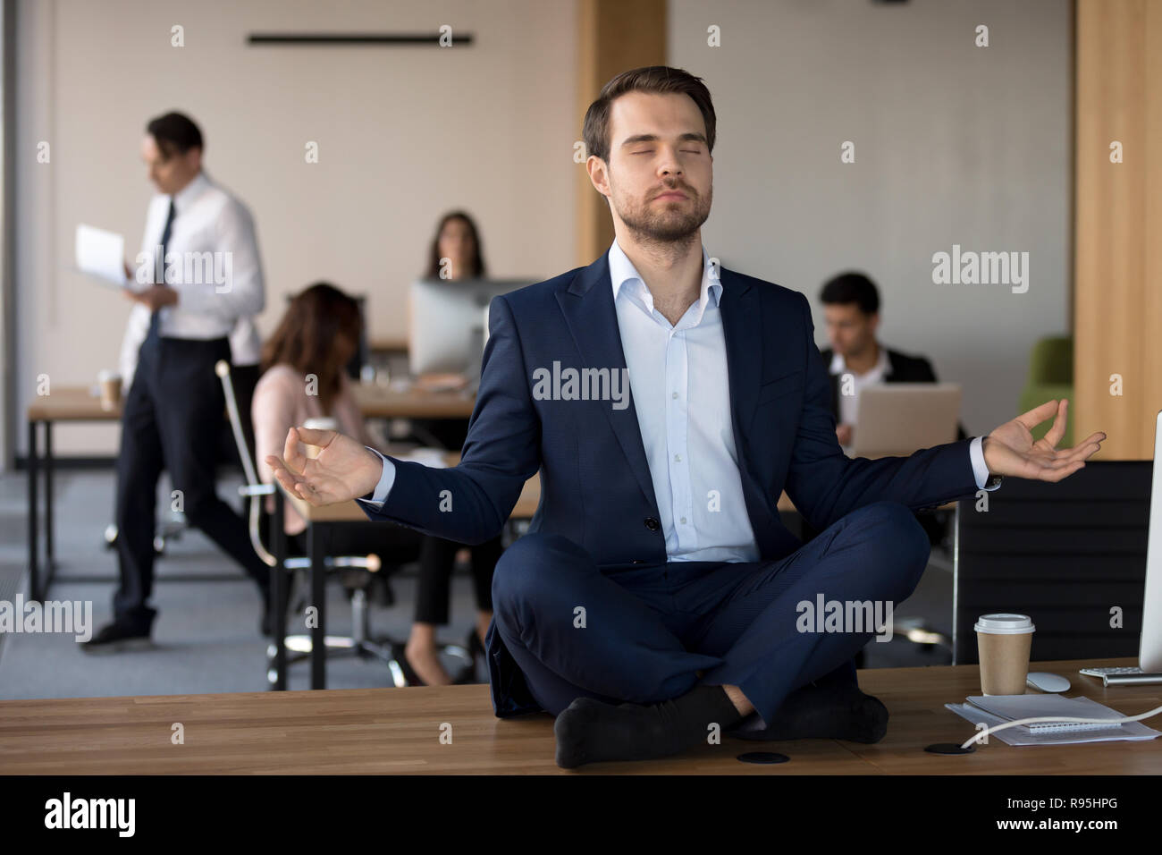 Geschäftsmann in Anzug sitzen am Tisch und Meditieren im Büro Stockfoto