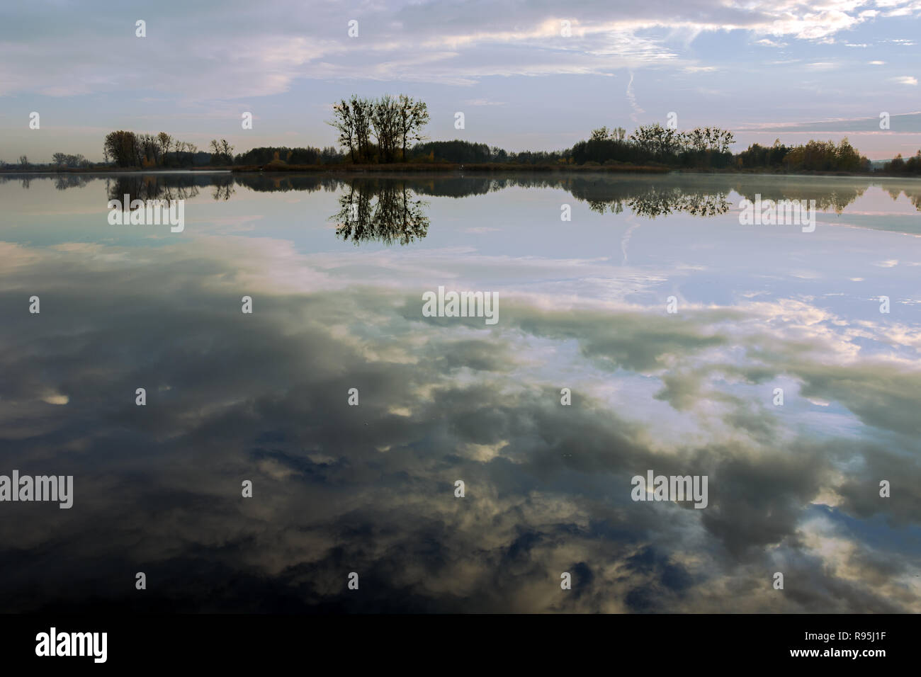 Die Reflexion der Wolken im Wasser eine ruhige See und Bäume am Ufer Stockfoto