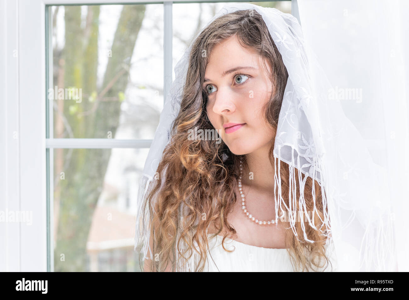 Closeup Portrait von jungen weiblichen Person, Frau, Braut im Brautkleid, Schleier, Schal, Gesicht, Perlenkette, Fenster, weiße Vorhänge, suchen Stockfoto