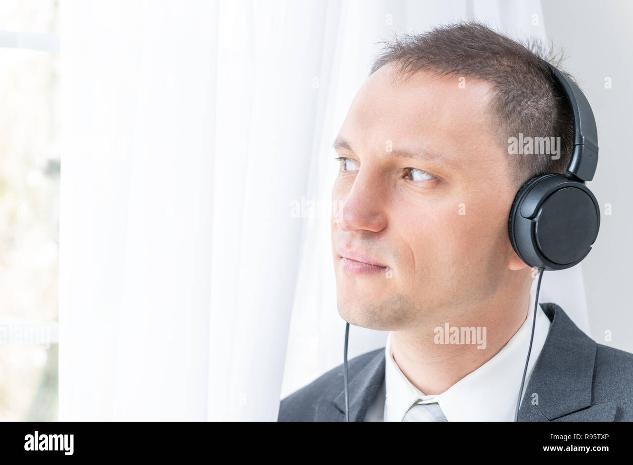 Nahaufnahme der junge, glückliche Menschen, männlich Geschäftsmann in grauen Anzug, Krawatte, Bräutigam, durch die Fenster in der Wohnung, Haus, Zimmer, weißen Vorhängen, mit Hea Stockfoto