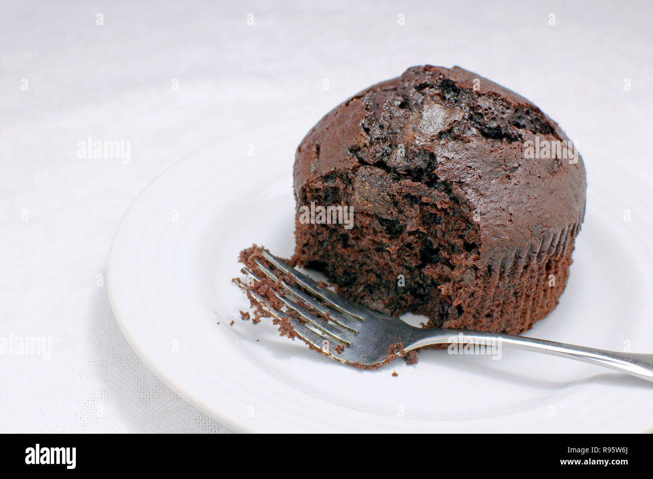 Teilweise gegessen Chocolate Muffin mit einer Gabel auf weißem Hintergrund Stockfoto
