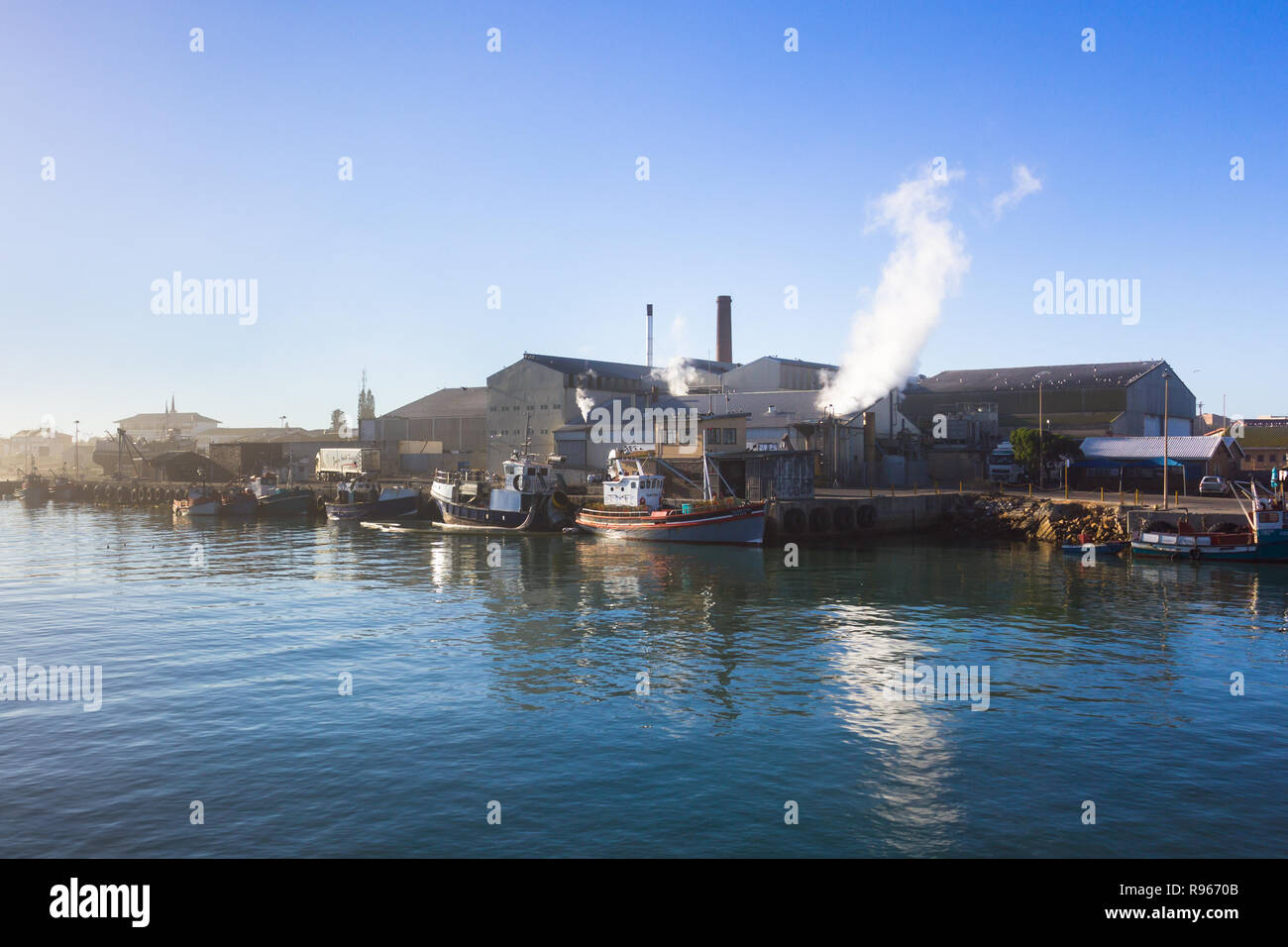 Fischfabrik an Lamberts Bay Hafen oder Hafen an der Westküste, am frühen Morgen mit Reflexionen im Meer angeln und Boote an der Kaje Stockfoto