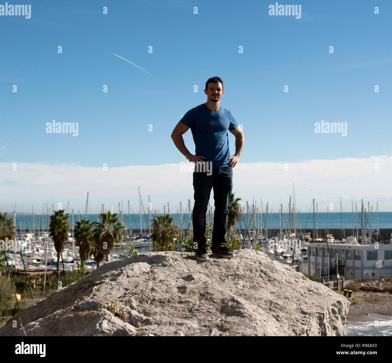 Junger Mann stehend auf Felsen in Garaff Spanien mit Blick auf das Mittelmeer Stockfoto