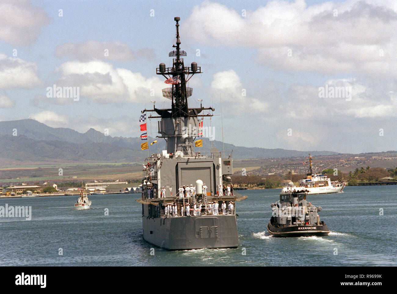 Der große Hafen schlepper WAXAHATCHIE (YTB 814) begleitet die USS BREWTON (FF 1086) weg vom Pier am Ende der Bezeichnung und Abschiedszeremonie für den unbekannten Soldaten der Vietnam ära. Die Fregatte ist Transport, das Unbekannte zu Naval Air Station Alameda, Kalifornien. Stockfoto