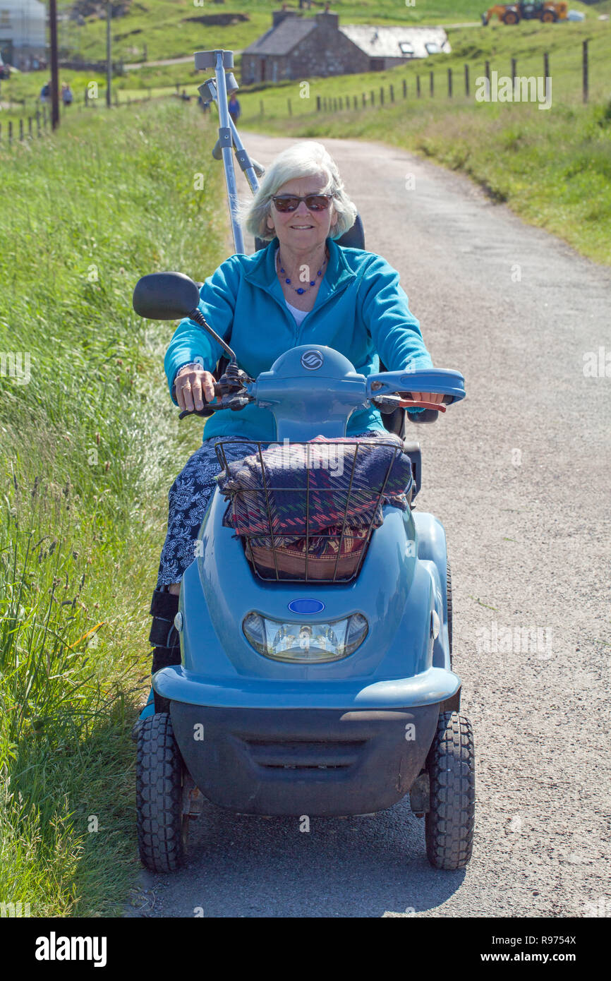 Physikalisch Frau älterer Bürger mit Mobilität Fahrzeug relativ unabhängigen Zugang zu den ländlichen Szene zu genießen beeinträchtigt. Die Insel Iona. Die Inner​​ Hebriden, an der Westküste von Schottland. Stockfoto