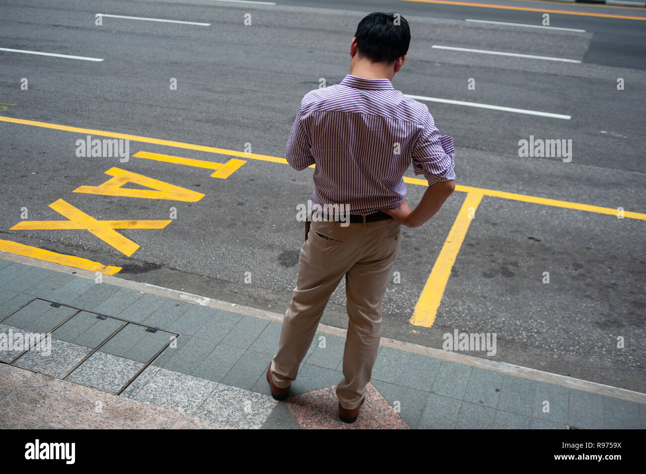 14.12.2018, Singapur, Republik Singapur, Asien - ein Mann wartet auf sein Taxi am Straßenrand in Singapore's Central Business District. Stockfoto