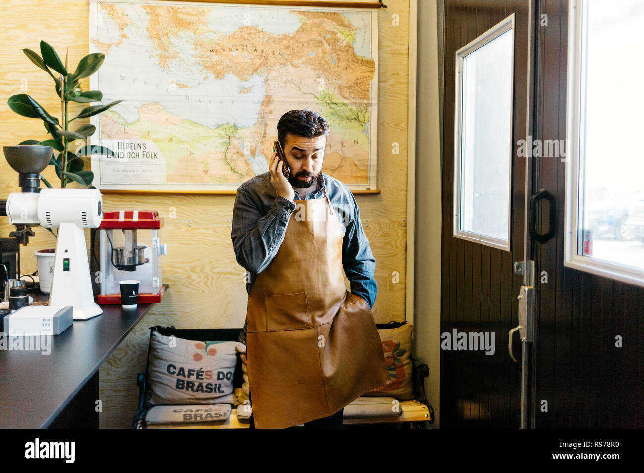 Inhaber kleiner Unternehmen in seinem kaffeeröster Shop über sein Mobiltelefon Stockfoto
