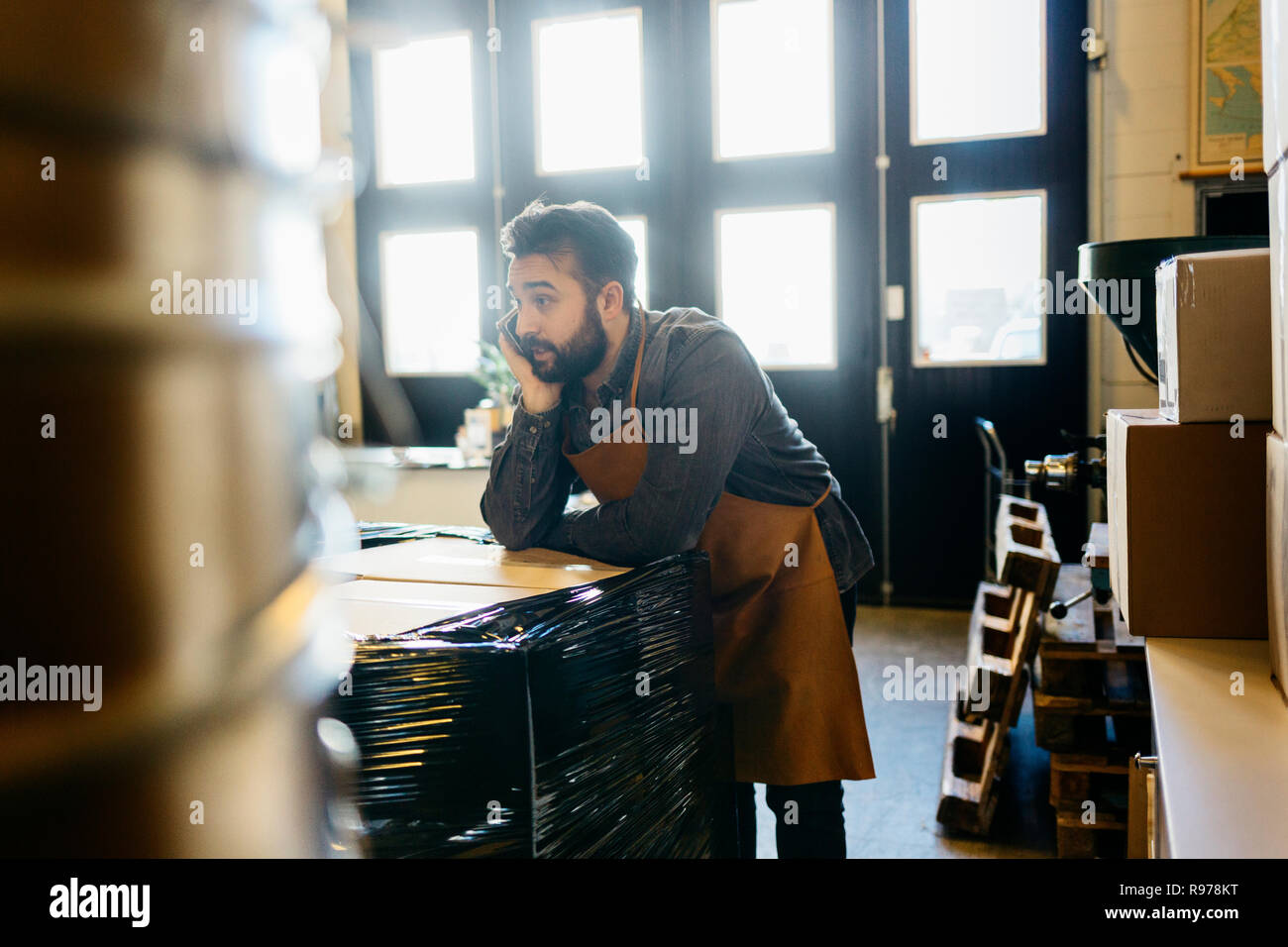 Inhaber kleiner Unternehmen in seinem kaffeeröster Shop über sein Mobiltelefon Stockfoto