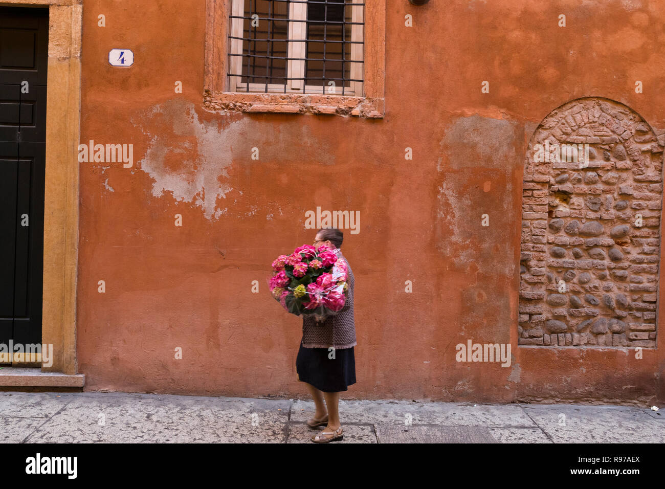 Eine Frau hält ein Bündel von Hortensie Blumen wie Sie ist zu Fuß in der Altstadt von Verona, Italien. Stockfoto