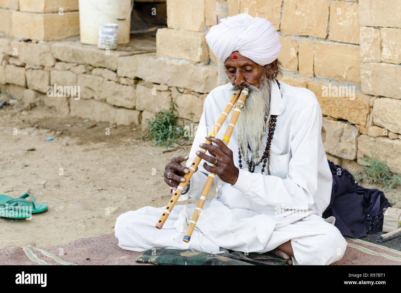 Alte indische Mann in weißer Kleidung spielen Doppel Flöten in Jaisalmer Wüste, Jaisalmer, Rajasthan, Indien Stockfoto