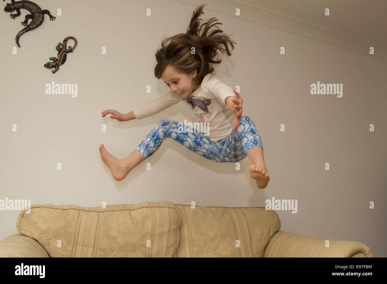 Kind, Mädchen im Haus springen, springen auf Möbel, Sofa, energisch, hyperaktiv, Spaß, sechs Jahre alt, Stockfoto