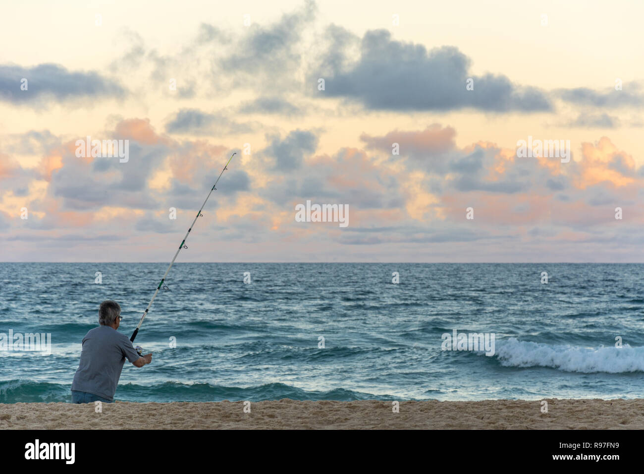 2018, Oktober. Florianopolis, Brasilien. Mann alleine Angeln mit der Rute in der Strand von Campeche. Stockfoto