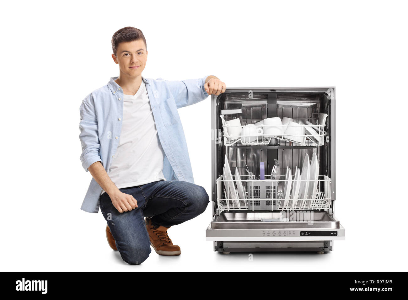 Junge Mann neben einem beladenen Spülmaschine auf weißem Hintergrund kniend Stockfoto