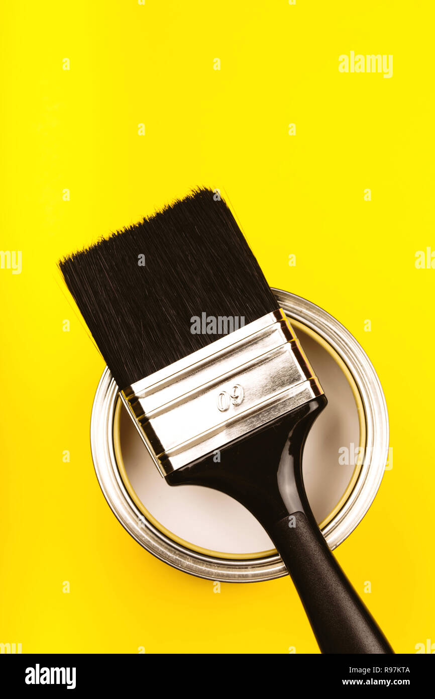 Bürste mit schwarzem Griff auf öffnen können von Farbe auf gelbem Hintergrund. Sanierungskonzept. Close Up. Stockfoto