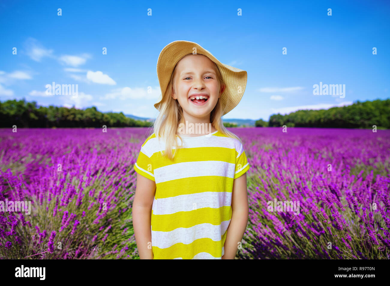 Portrait von lächelndes Kind in gelben T-Shirt und Strohhut im lavendelfeld in der Provence, Frankreich. Herrliche Aussicht auf das Plateau von Valensole mit blühenden Lave Stockfoto