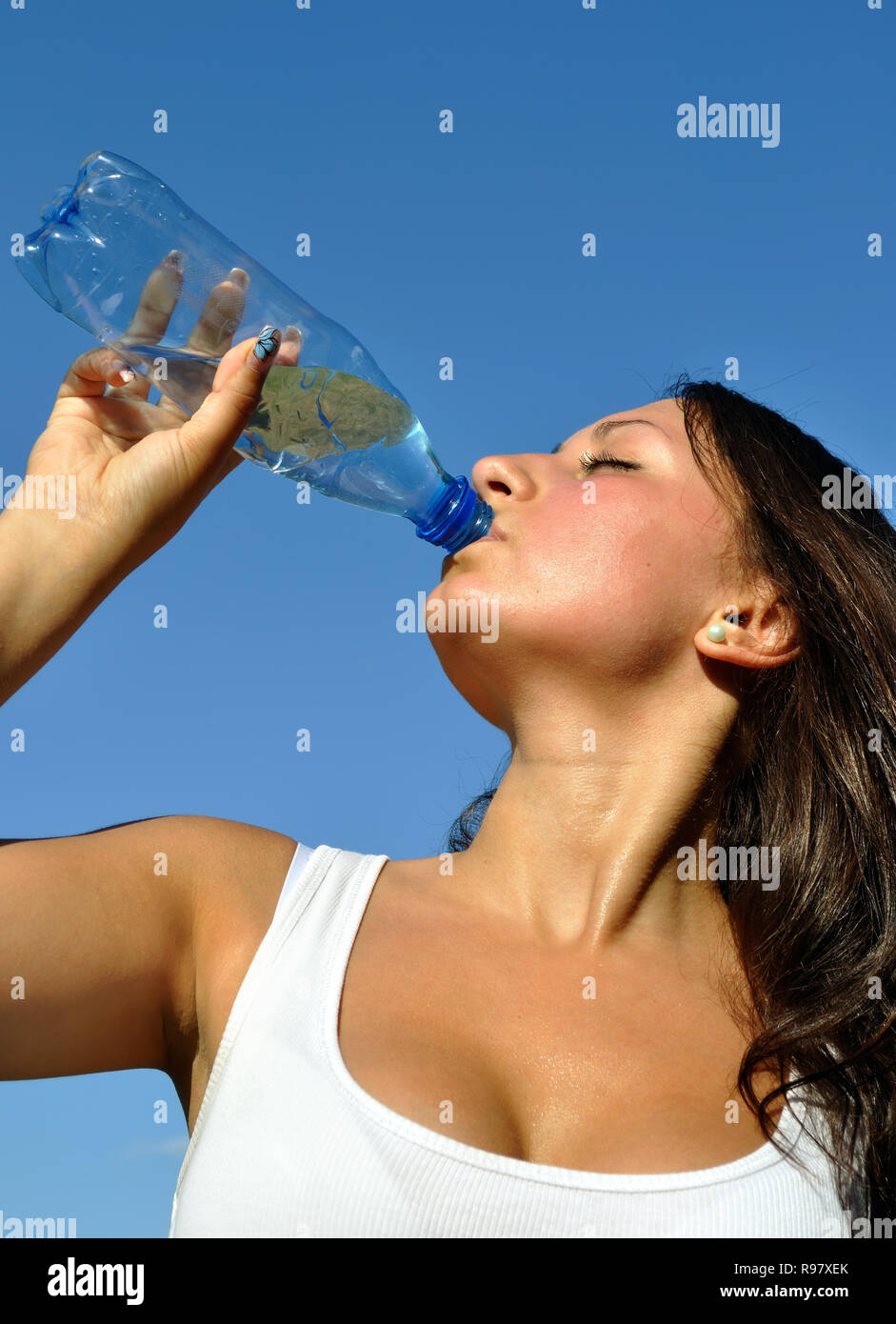 junge sportliche Frau trinkt kaltes Wasser in heißen Tag, vertikale Zusammensetzung Stockfoto