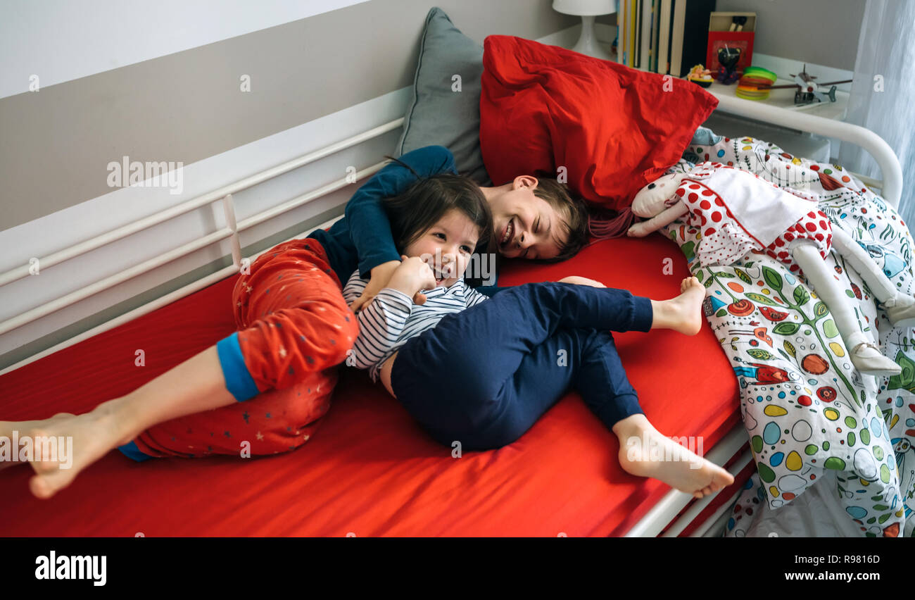 Brüder kitzeln und Lachen auf dem Bett liegend Stockfoto