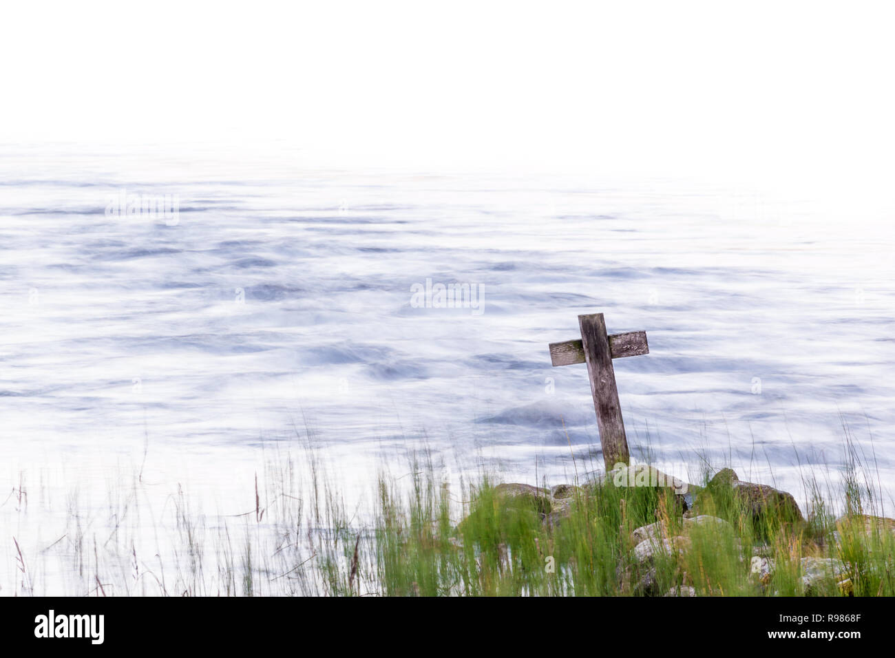 Holzkreuz auf einem Ufer mit streaming Wasser im Hintergrund Stockfoto