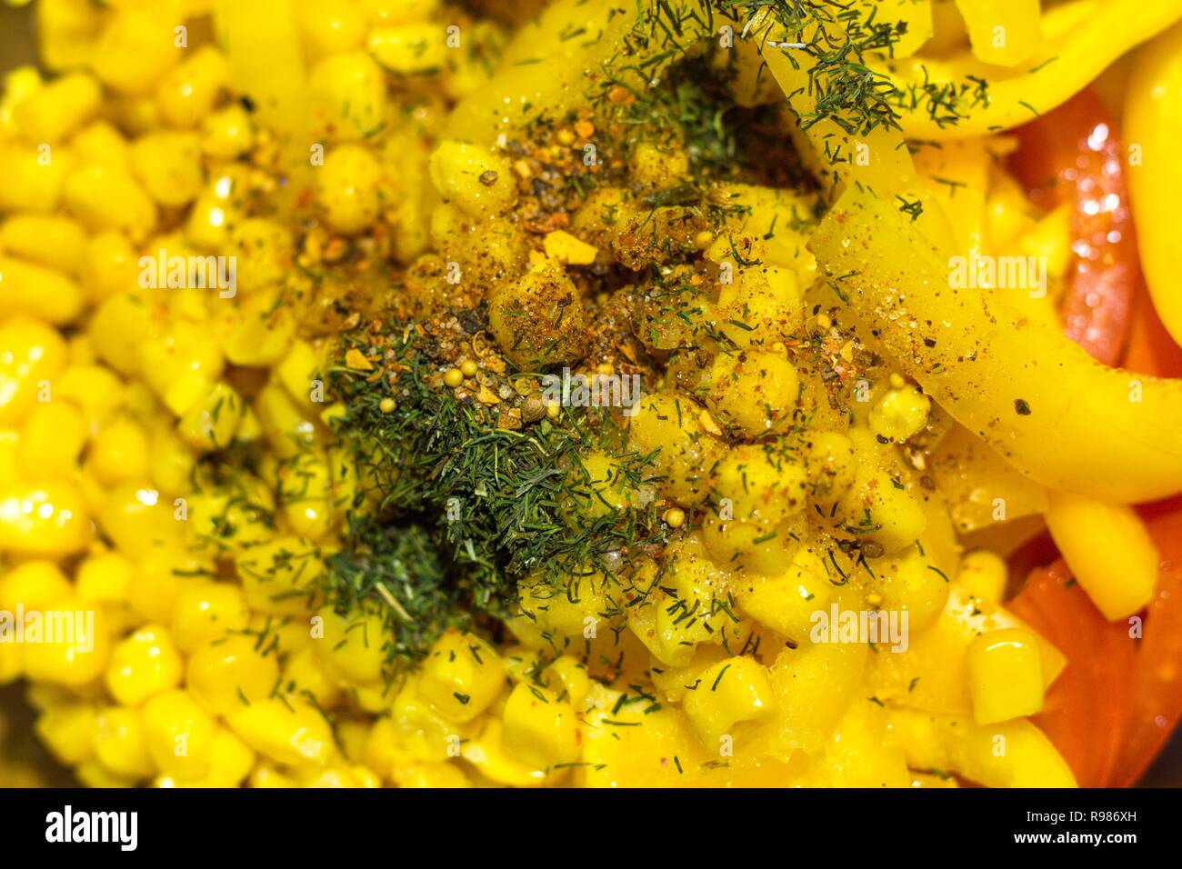 Mais, gelbe Paprika und Tomaten sind für das Kochen von Gemüse Salat geschnitten. Bestandteile sind bestreut mit verschiedenen Gewürzen und Pfeffer. Stockfoto