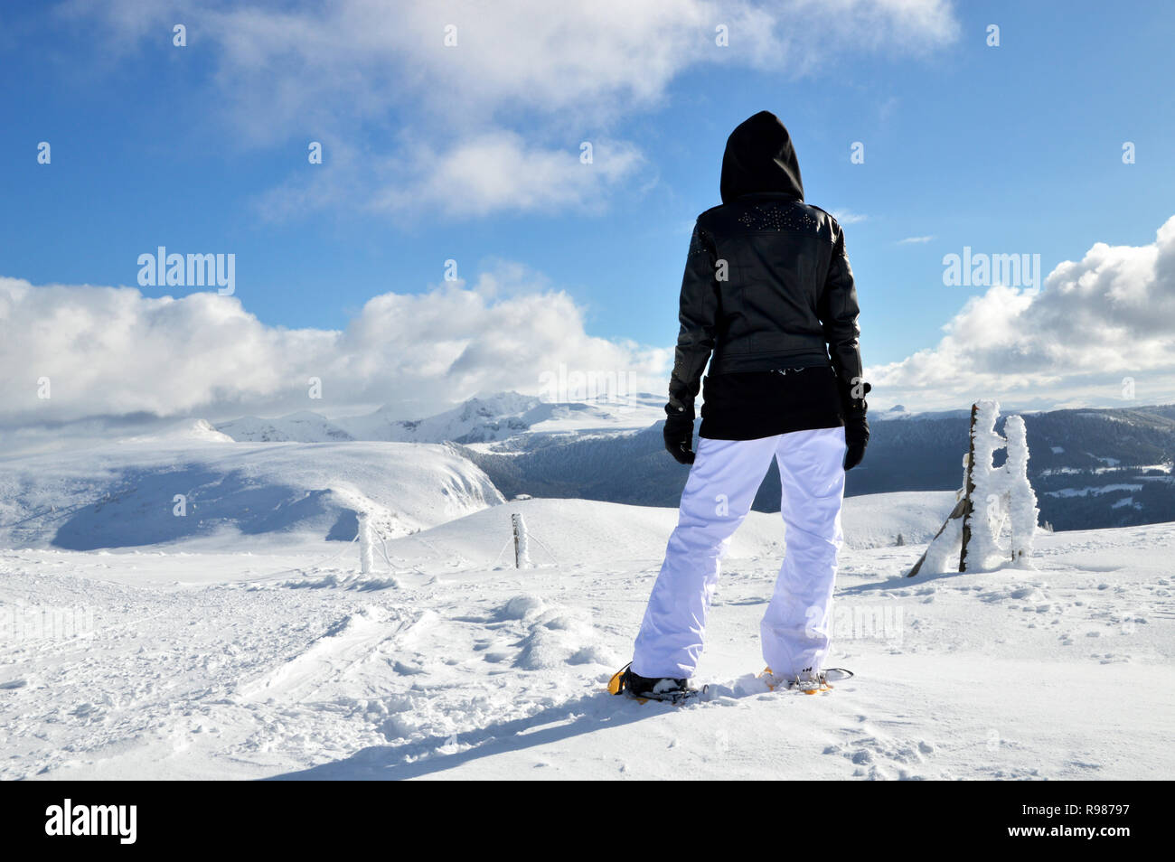 Eine Person mit Schneeschuhen auf einem verschneiten Berg, vor einem Vulkan Kette in der Auvergne Stockfoto