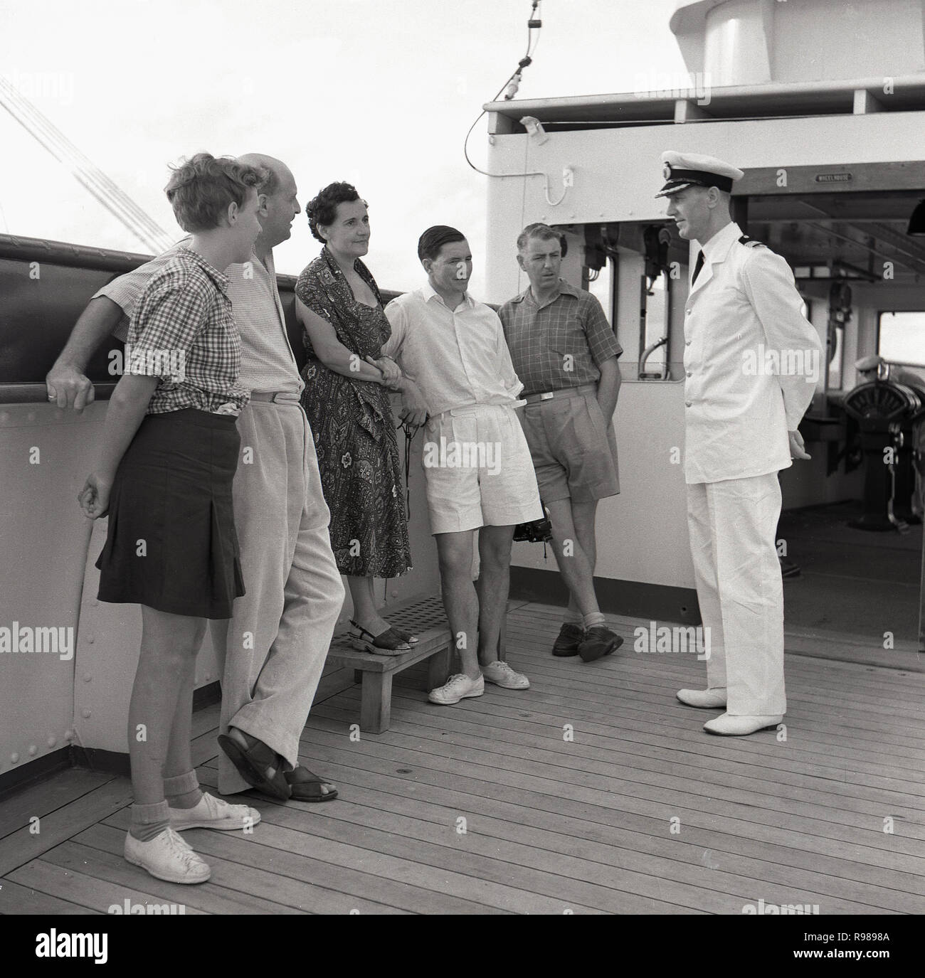 1950, historische, auf dem Deck der Brücke von einer Union - Schloss Steamship, Kapitän des uniformierten Schiff im Gespräch mit einigen Passagieren. Stockfoto