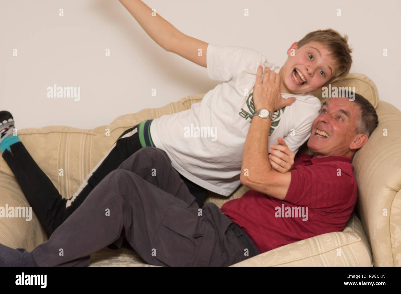 Großvater oder Vater kämpfen, spielen, kämpfen, Ringen, spielen rauh, mit Sohn oder Enkel, Jugend, zwölf Jahre alt -, auf dem Sofa Sofa, Spaß zu haben. Stockfoto