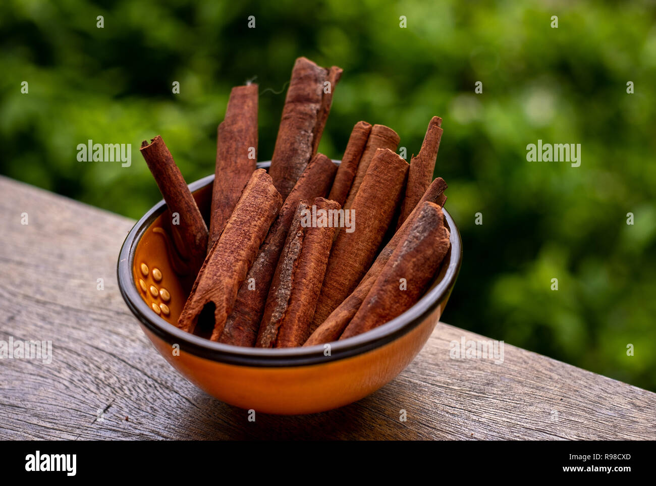 Ansicht in der Perspektive einer bunten türkischen kleine Schüssel auf Holzbrett mit Zimt - Zimt Serum - ein Gewürz Zutat. Grüner Hintergrund. Stockfoto