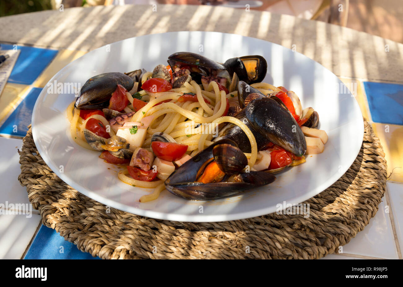Platte mit Meeresfrüchten Pasta auf sonnenbeschienenen Tisch in Italien. Stockfoto