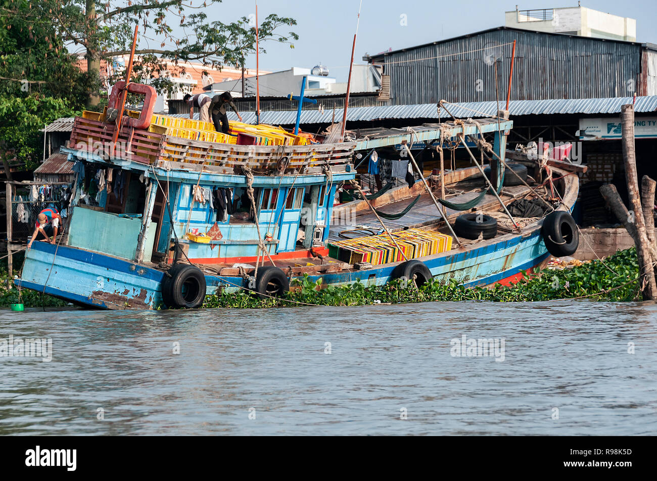 Männer ein sehr overladen Holzboot in Can Tho, Mekong Delta, Vietnam entladen Stockfoto