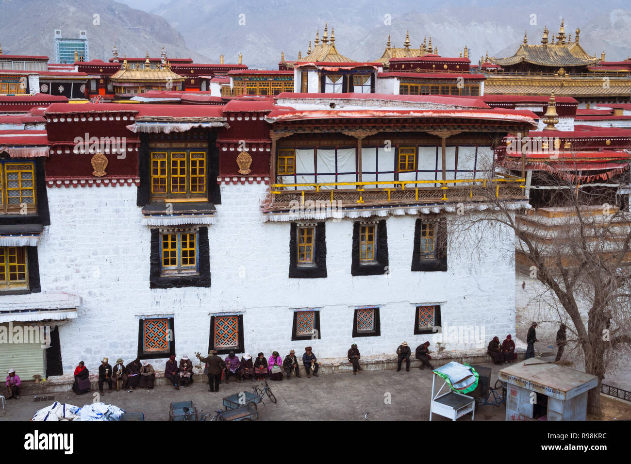 Lhasa, Tibet autonomen Region, China: Menschen sitzen auf einer Seite der Jokhang Tempel. Der Jokhang ist als der heiligste Tempel in Tibet betrachtet. Firs Stockfoto