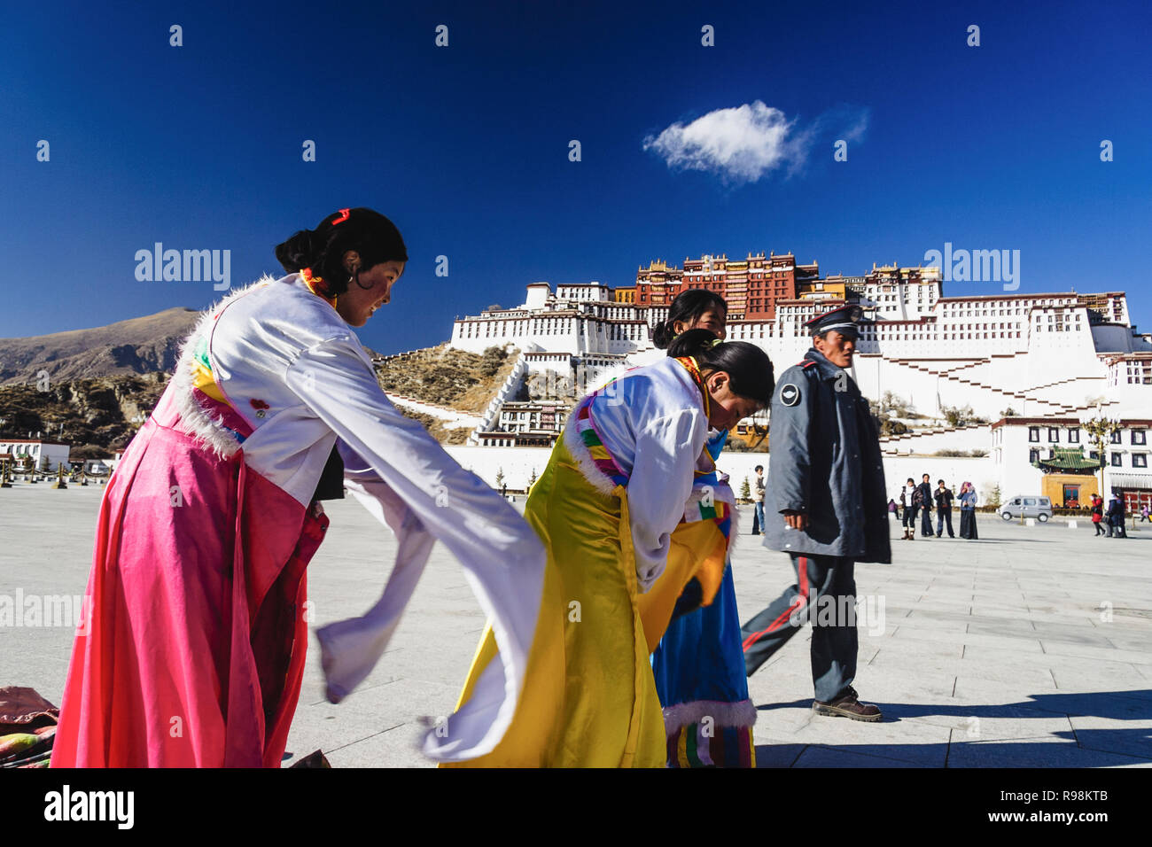 Lhasa, Tibet autonomen Region, China: Ein chinesischer Polizist Spaziergänge letzten drei tibetischen Frauen heraus versuchen, traditionelle Kostüme Neben Potala-palast. Fir Stockfoto