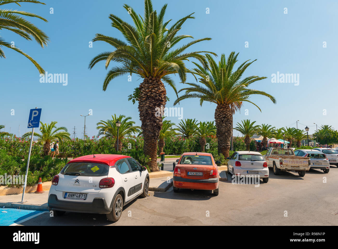 Rethymno, Griechenland - AUGUST 2018: Unterschiedliche Autos sind unter Palmen bei Rethimnon Stadt geparkt Stockfoto