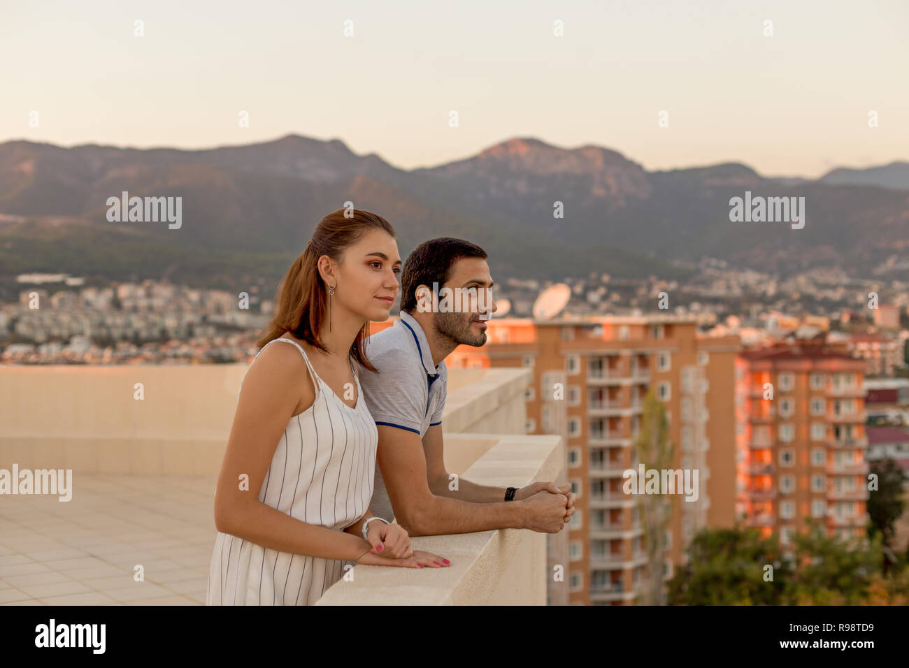 Junges Paar im Sommer Outfit genießen Sie die Stadt und die Aussicht von der Dachterrasse. Horizontale erschossen. Stockfoto