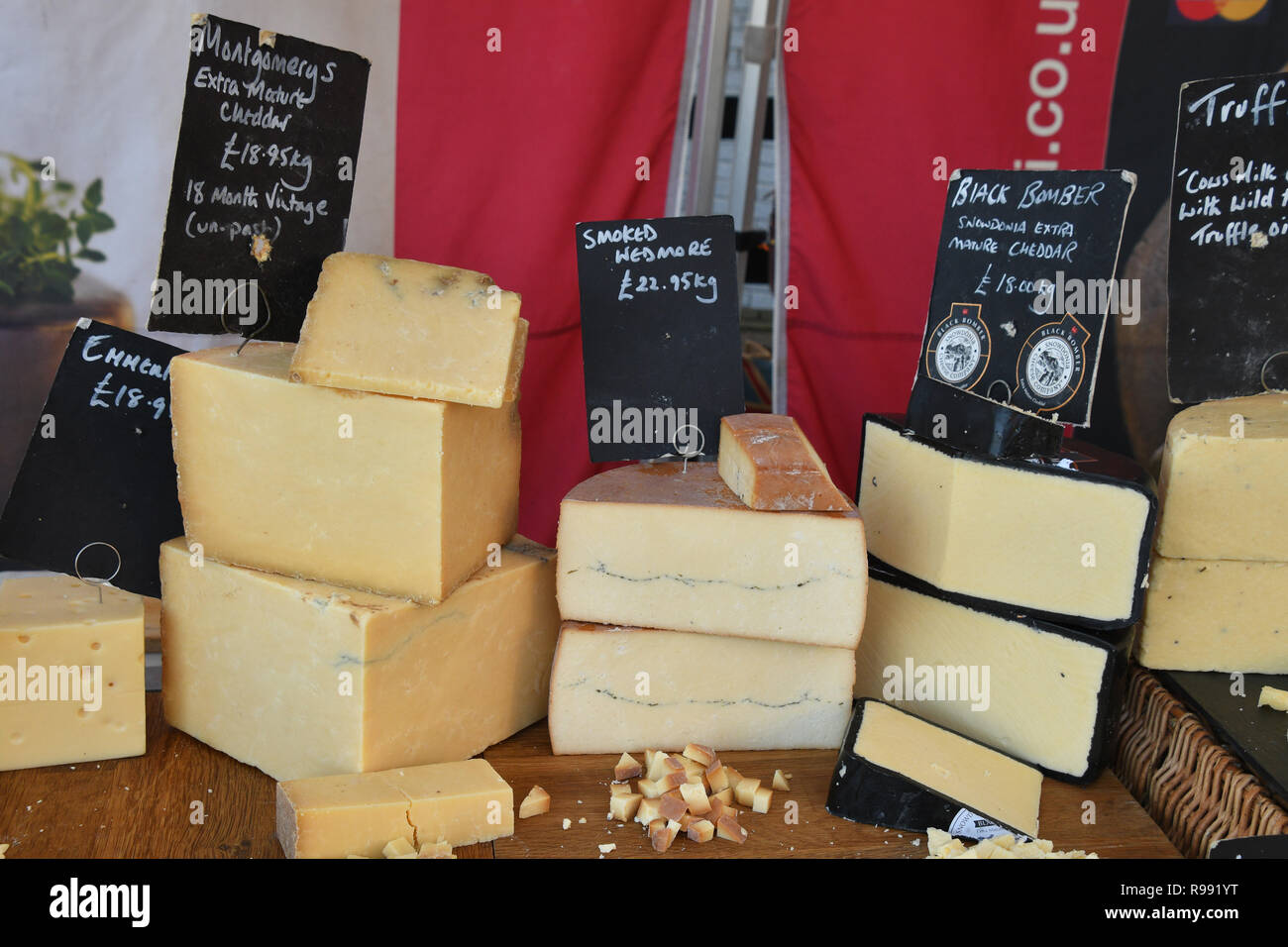 Cheddar Käse auf Marktstand mit Proben für die Verkostung angezeigt. Montgomery's Extra reifen, geräucherte Wedmore, schwarze Bomber Snowdonia Extra Reifen, Stockfoto
