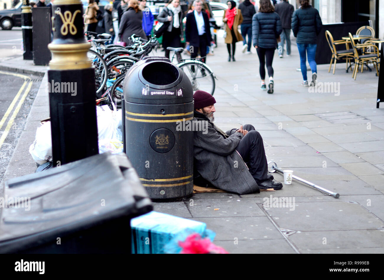 Obdachloser mit einer Krücke auf der Straße betteln in London, England, UK. Stockfoto