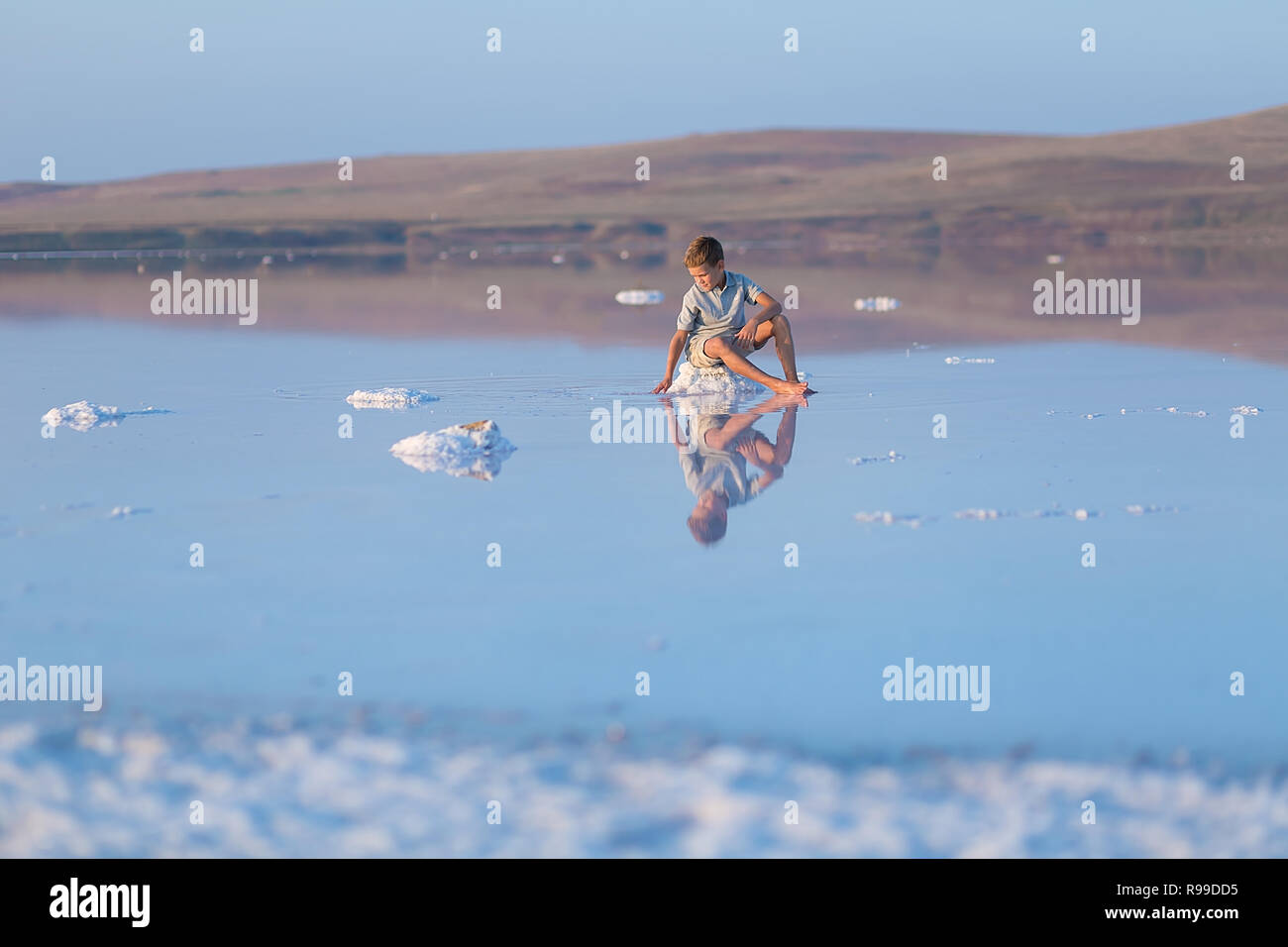 Ein Junge geht am Ufer des Sees entlang. Ein Salt Lake Shore. Ein Salt Lake Stockfoto