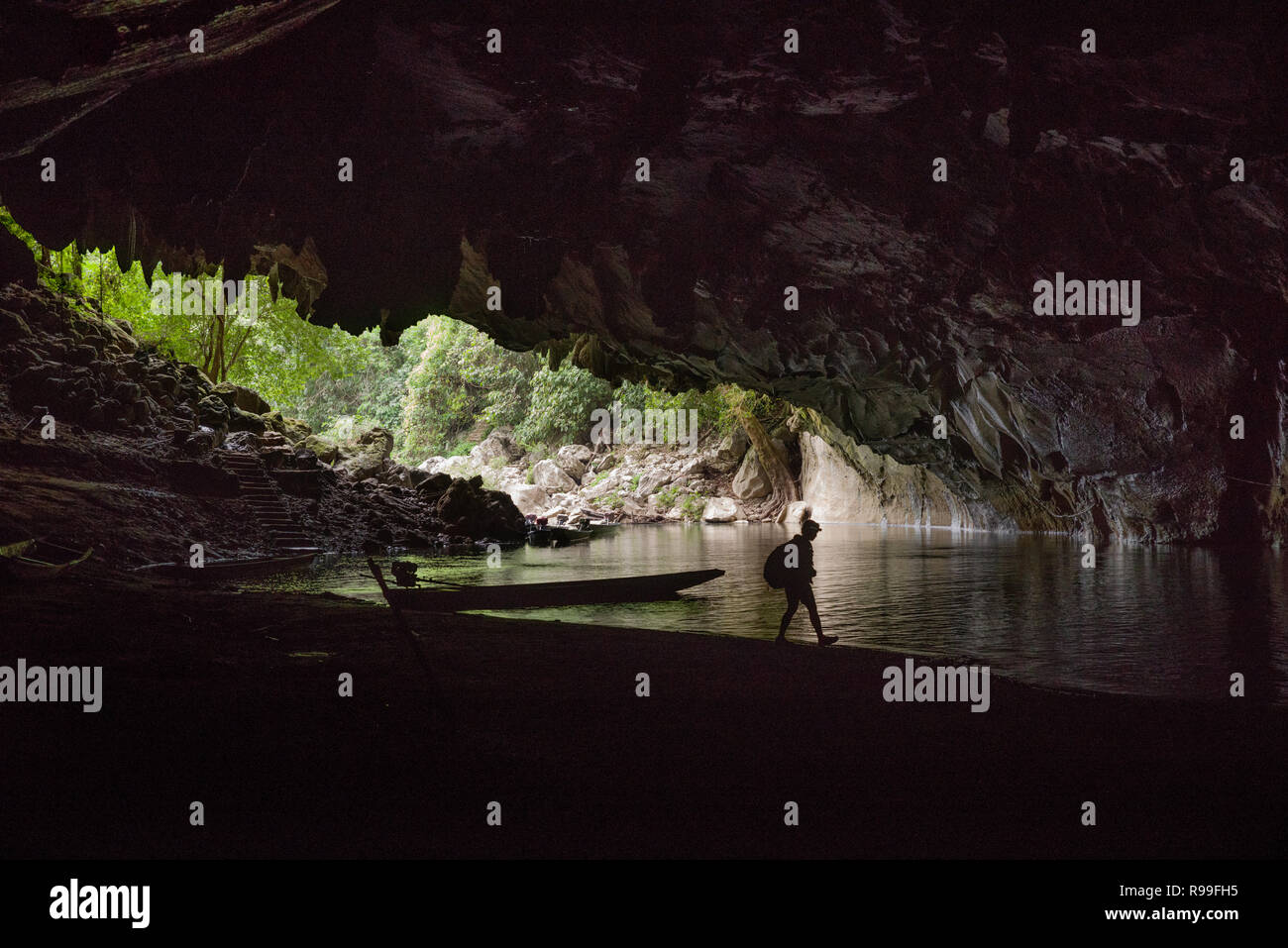 Silhouette einer Frau zu Fuß durch die Ufer in der Eingang zur Höhle Konglor in Laos. Stockfoto