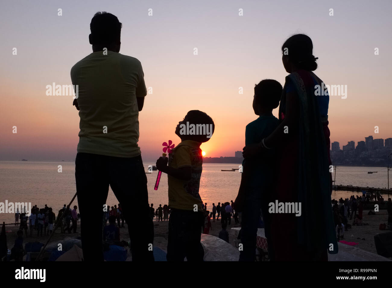 Eine Kleinfamilie in Mumbai, Indien, darunter zwei Kinder, genießen den Sonnenuntergang am Marine Drive, einem Boulevard entlang der Arabischen See Stockfoto