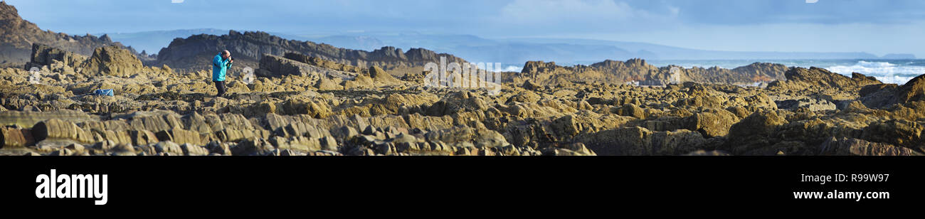 Ein einsamer Fotograf auf einer felsigen Küste Stockfoto