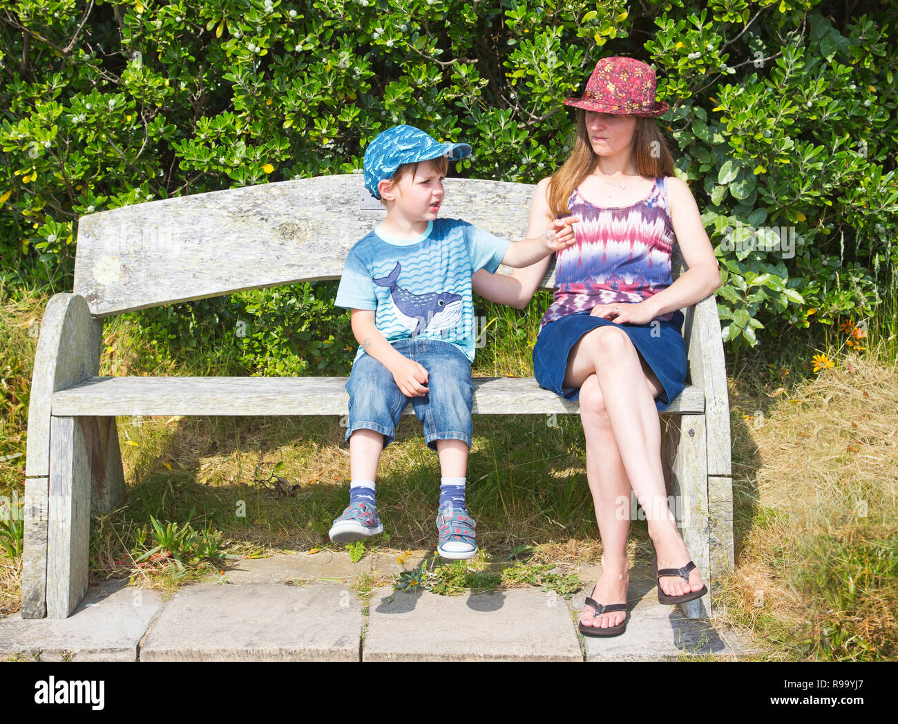 Ein kleiner Junge mit seiner Mutter auf einer Holzbank Stockfoto