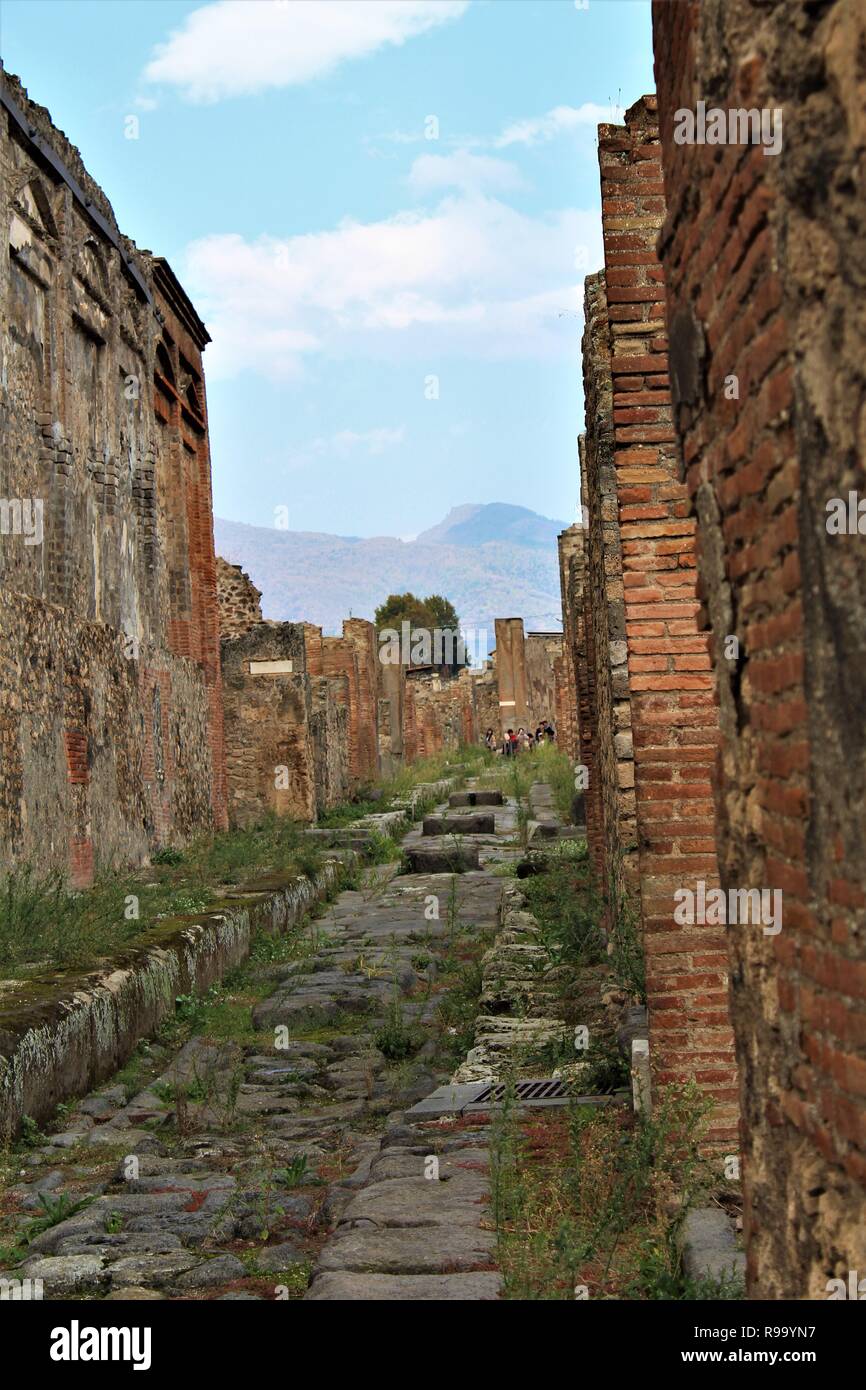 Pompeji, Italien - 23. Oktober 2018: ein Blick auf eine zerstörte Straße in der antiken Stadt Pompeji, mit dem Vesuv Vulkan im Hintergrund. Stockfoto