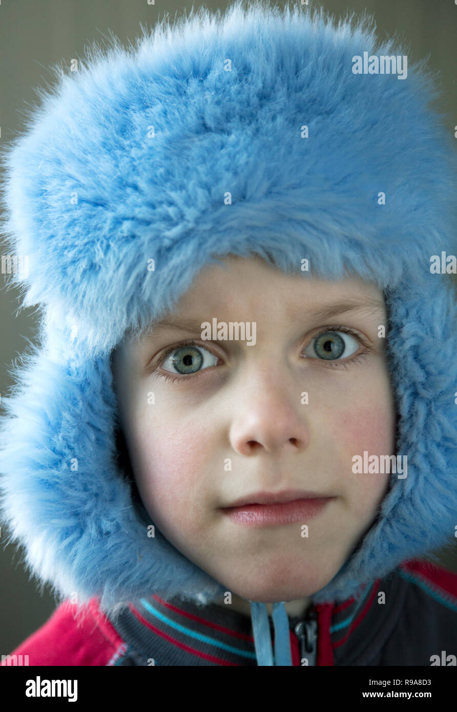 Junge in eine Kappe mit Ohrenschützern mit Ausbauchende Augen schließen, Stockfoto
