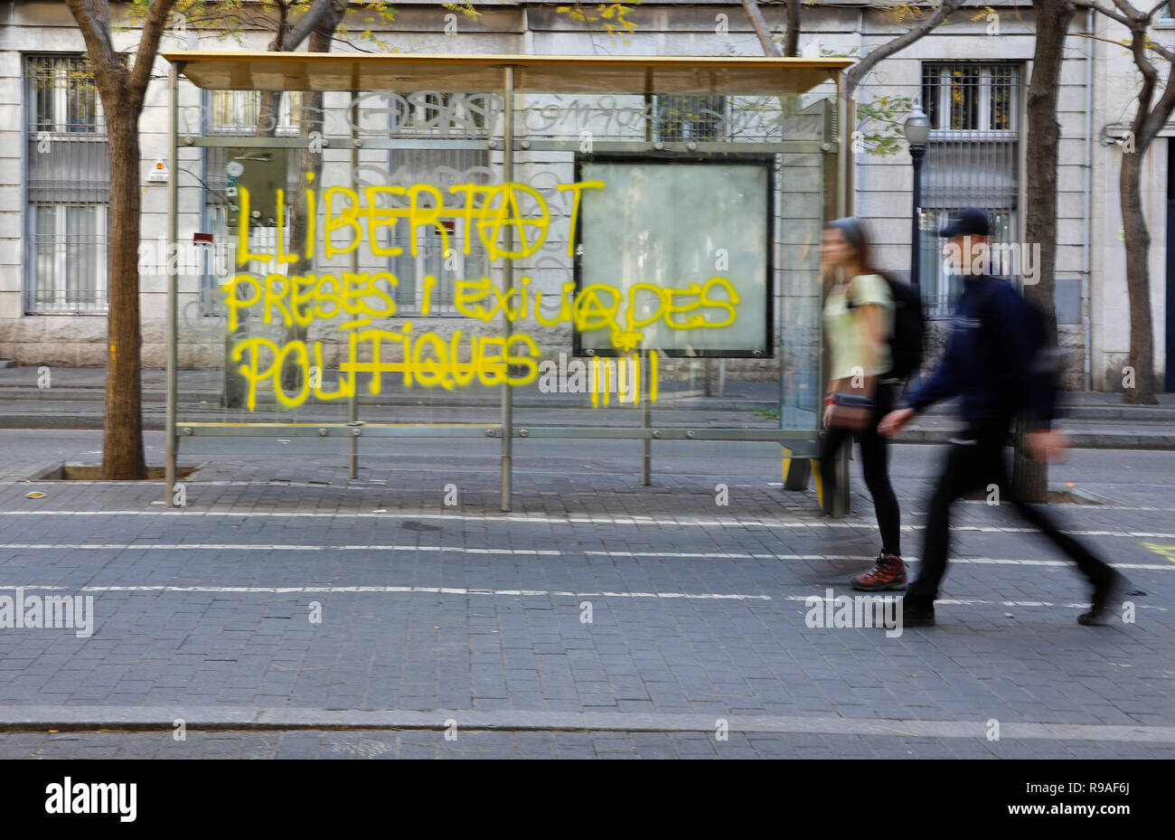 Barcelona, Spanien. 21 Dez, 2018. Zwei Personen Pass eine Bushaltestelle mit dem Graffiti "die Freiheit der politischen Gefangenen und Vertriebene" besprüht. Tausende von Menschen in der Region Katalonien haben protestiert gegen eine Sitzung der spanischen Zentralregierung in Barcelona, als "Provokation" kritisiert worden. Credit: Clara Margais/dpa/Alamy leben Nachrichten Stockfoto