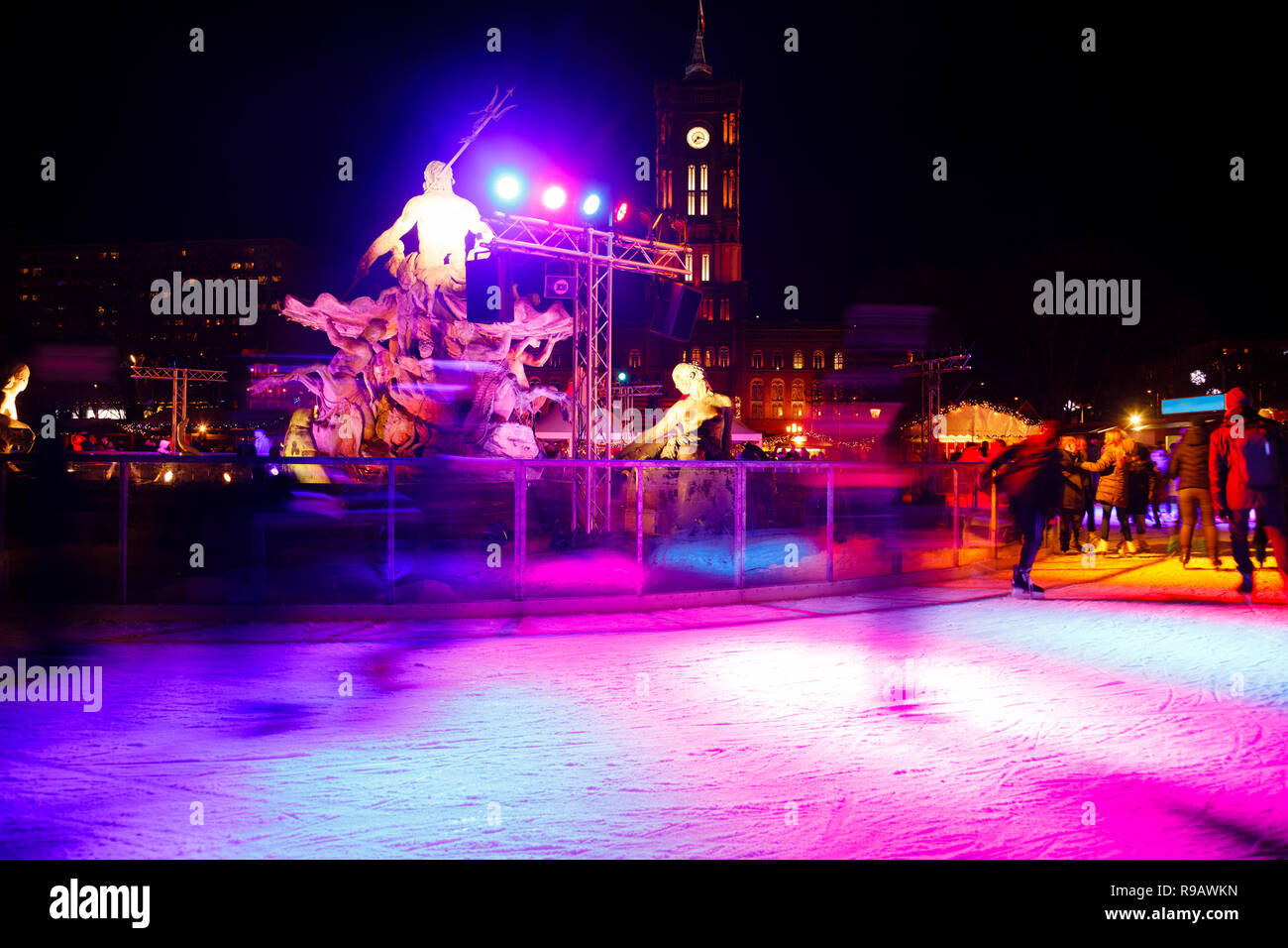 Leute Eislaufen auf der Eisbahn am Weihnachtsmarkt in Mitte, Berlin, Deutschland in der Nacht. Skater sind verschwommen in Bewegung. Rote Stadt Hall (Rotes Rathaus Stockfoto