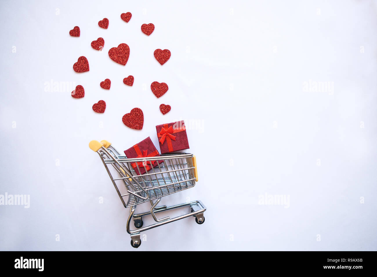 Einkaufswagen mit Geschenkboxen und Herzen. Das Konzept der Holiday Verkauf Valentinstag und Tag der Frauen. Stockfoto