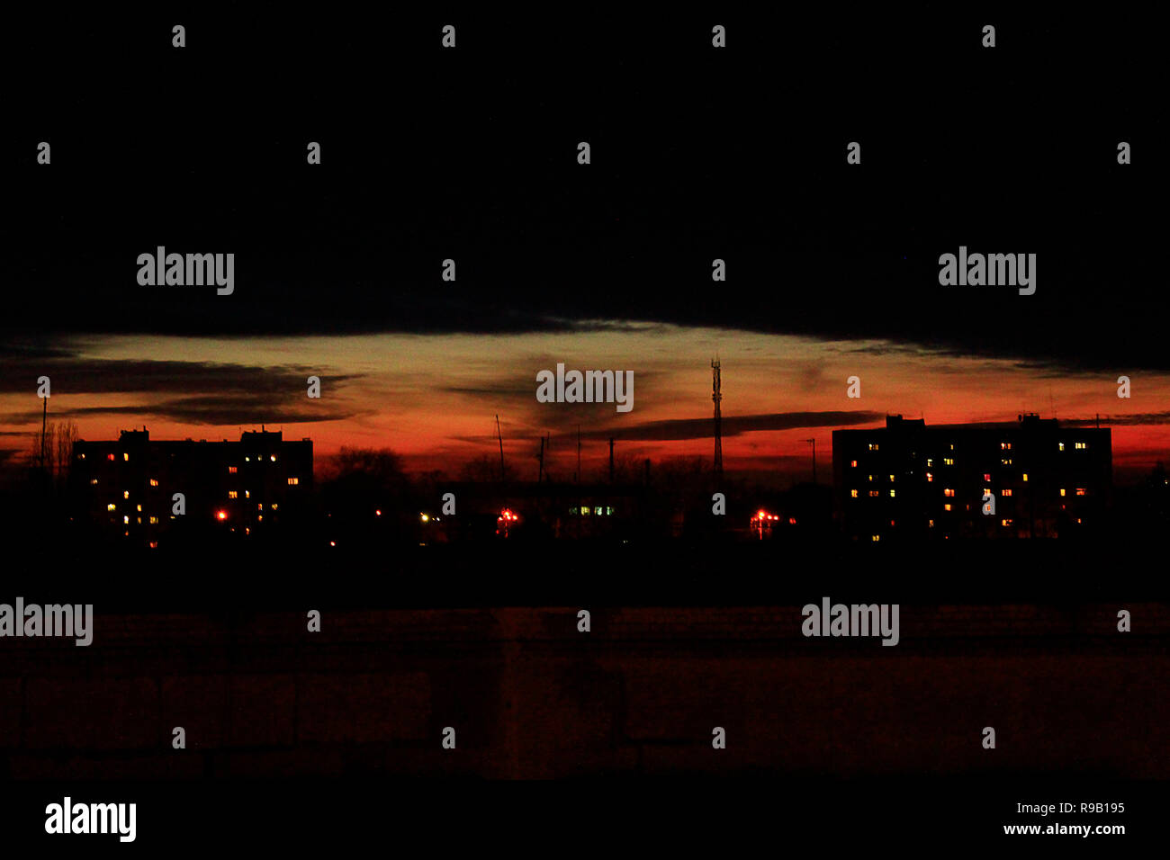 Dunkle Sonnenuntergang über mehrstöckigen Haus. Abend Stadtbild. Stadt Landschaft. In der Stadt der Dämmerung. Dämmerung mit Zinnoberrot Sonnenuntergang Stockfoto